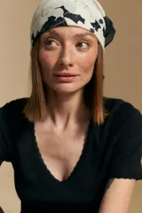 Remera de manga corta en tejido acanalado, con escote en V y detalles de puntilla en el borde del escote y en las mangas. Presenta un ajuste entallado al cuerpo.