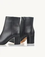 Bota de cuero negra con caña baja, punta fina y taco cuadrado.