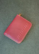 Billetera de cuero color tostado con cierre de cremallera. Interior con seis compartimentos para tarjetas y un compartimento para monedas con cierre. El billete entra doblado.