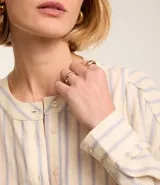 Vestido chemise midi de corte camisero, con escote en pico y botonadura frontal parcial. Presenta mangas 3/4 y un diseño de rayas verticales en tonos claros.