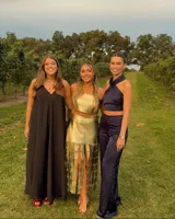 Conjunto de dos piezas confeccionado en cuero genuino color dorado, compuesto por un top strapless de corte recto y una falda midi con diseño de tiras verticales entrelazadas en el ruedo.