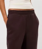 Pantalón estilo aladín de corte amplio y holgado, color marrón chocolate. Confeccionado en tejido de moletón con felpa interna, cuenta con cintura elástica y puños elásticos en los tobillos.