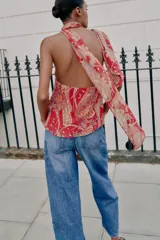 Top rojo con estampado estilo paisley, diseño de cuello halter con lazo, espalda descubierta y detalles de volantes en capas en el frente.