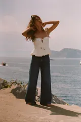 Top blanco de lino con tirantes finos, escote recto, detalle de frunces y cordón ajustable con abalorios.