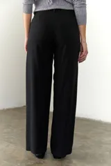 Pantalón marrón de corte recto y pierna ancha, con cintura alta, bolsillos laterales y cierre.