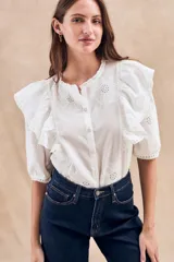 Blusa blanca de algodón con bordado floral, cuello redondo, manga corta con volados y cierre frontal con botones.