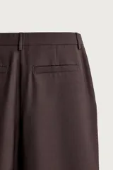 Pantalón de traje straight fit color marrón oscuro, confeccionado en tejido con lana. Cuenta con bolsillos frontales, bolsillos traseros de vivo y cierre frontal con cremallera y gancho metálico oculto.