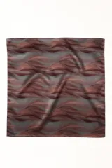 Pañuelo cuadrado de satén con estampado abstracto en tonos rojizos y grises, anudado en la parte inferior.