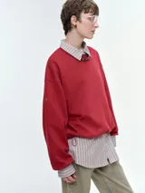 Buzo oversize de corte amplio y relajado, color rojo, con cuello redondo acanalado, mangas anchas y bajo regulable mediante elásticos.