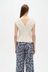 Blusa de lino color blanco, con cuello en V, pinzas de entalle y diseño al cuerpo con faldón acampanado.