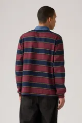 Remera tipo polo de manga larga con diseño a rayas horizontales en tonos bordó, azul marino y amarillo. Presenta cuello de denim con cierre de botones y pequeño logo de la marca en el pecho.