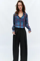 Camisa de manga larga con cuello solapa y cierre frontal con botones. Presenta un diseño de cuadros en tonos azules y rojos sobre un tejido semitransparente.