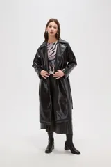 Trinchera de eco-cuero en color bordó, con diseño de doble botonadura, solapas amplias y cinturón ajustable en la cintura. Presenta mangas largas con detalles en los puños y bolsillos laterales.