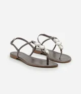 Sandalia plana color dorado, con diseño de tiras finas y aplicación de pedrería decorativa en la parte central. Cuenta con cierre de hebilla lateral ajustable.