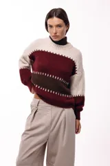 Sweater de tejido de punto grueso con diseño de bloques de color en tonos beige, marrón y bordó. Presenta un corte relajado, mangas amplias y detalles de costuras visibles en contraste que separan las franjas de color.