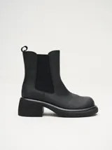 Bota tipo chelsea de cuero vacuno en color rojo con estampado floral grabado en negro. Presenta paneles laterales elásticos, suela de plataforma y taco cuadrado en color negro.