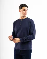 Remera tipo henley de manga larga confeccionada en tejido de algodón con textura mini piqué. Presenta un cierre frontal con tres botones y puños ajustados en las mangas.