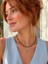 Collar de piedra natural ojo de tigre con pequeñas cuentas doradas y un dije rectangular colgante de acero con baño en oro y detalles grabados.