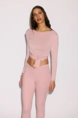 Top cropped de yoga de punto modal suave en color rosado, con mangas largas, escote en V pronunciado y diseño cruzado con tira para anudar al frente.