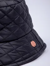 Gorro tipo bucket color beige con diseño acolchado de rombos y pequeño logo circular en el lateral.