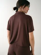 Camisa de manga corta para dormir de color rosado, confeccionada en viscosa. Presenta botones frontales, cuello con solapa, bolsillo en el pecho y ribetes a tono.