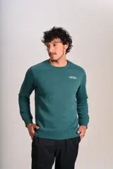 Buzo verde oscuro de cuello redondo, mangas largas con puños elásticos y pequeño estampado ovalado en el pecho.