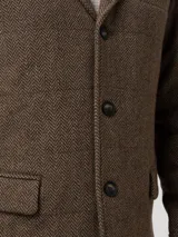 Chaqueta de hombre color marrón con patrón de espiga, cuello con solapa, cierre de tres botones y bolsillos frontales con solapa.