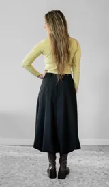 Pollera midi de corte balloon, color negro, confeccionada en gabardina. Presenta un diseño de cintura alta con lazo ajustable y ruedo con volumen.
