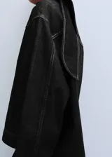 Blusa de mezclilla negra con costuras en contraste, cuello alto y solapa trasera.