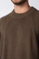 Sweater de tejido grueso con cuello redondo, mangas largas con puños acanalados y corte relajado.