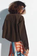 Cazadora de mezclilla color verde militar con cuello de solapa, manga larga, bolsillos delanteros de parche y cierre frontal con botones metálicos.