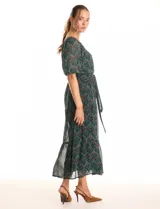 Vestido midi de gasa estampada en tonos verdes y marrones, con escote en V cruzado en la parte delantera y escote redondo elastizado en la espalda. Presenta cintura elastizada con lazo fino para anudar, mangas cortas evasé con volumen y falda con volados escalonados. Incluye forro interno a tono.
