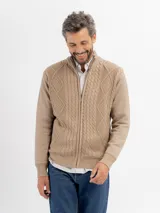 Campera tejida de punto en color beige, con diseño de trenzas y rombos, cuello alto y cierre frontal completo.