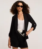 Blazer negro de sastrería confeccionado en tejido airflow con textura arrugada, cuello con solapa, bolsillos delanteros y mangas 3/4 con martingalas en los puños.