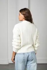 Buzo de tejido de punto con diseño de ochos, cuello redondo y mangas largas con puños acanalados.