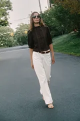 Blusa blanca de cuello alto con detalles de puntilla, manga corta abullonada y cierre posterior con botón.