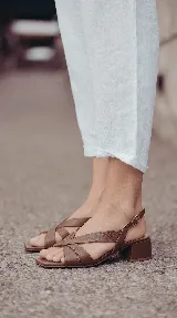 Sandalia de cuero color chocolate con tiras cruzadas en el empeine, talón descubierto con tira ajustable y taco cuadrado bajo.