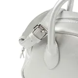 Cartera estilo bowling marca XL Extra Large, color plateado, confeccionada en símil cuero. Cuenta con asas fijas de mano y una correa larga regulable y desmontable. Posee cierre superior y detalle de placa metálica con el logo de la marca en el frente.
