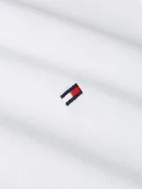 Chomba blanca de piqué con textura tipo diamante, cuello tipo chomba, cartera de cinco botones y logo de Tommy Hilfiger bordado en el pecho.