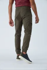 Pantalón cargo color verde oliva, de corte slim, con cintura elastizada y cordón ajustable. Presenta bolsillos laterales tipo cargo con botones y puños elásticos en los tobillos.