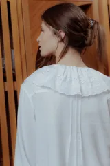 Camisa blanca de lino con cuello babero de broderie y mangas largas.