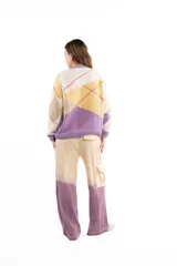 Cárdigan de punto con diseño de rombos en tonos crema, amarillo, beige y lila. Presenta cierre frontal con botones, cuello redondo y puños acanalados en color lila.