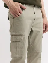 Pantalón de gabardina color marrón, corte slim fit, con bolsillos laterales tipo cargo.