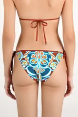 Calzón de bikini con diseño estampado colorido y tiras ajustables en los laterales con apliques metálicos.