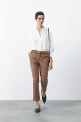 Pantalón de sastrería color marrón, de corte recto y tiro medio. Presenta una cintura estructurada con detalle de línea oscura en el borde superior y costuras frontales marcadas que estilizan la silueta.