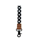 Llavero de muñeca con correa de poliéster negra con estampado de lunares blancos, presilla de cuero sintético marrón y gancho metálico negro con mosquetón.