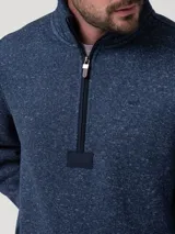 Polar de tejido jaspeado azul marino con cuello alto y cierre frontal parcial con tirador de cuero. Presenta bolsillos laterales con cierre.