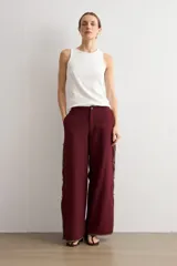 Pantalón ancho color bordó de talle alto, con abertura lateral decorada con ribete contrastante y cierre de botones tipo nudo chino.