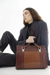 Cartera tipo shopper de cuero genuino marrón con panel central de textura símil cocodrilo y herrajes metálicos plateados.