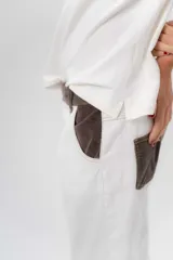 Pantalón de gabardina azul marino, de corte barrel y tiro bajo, con detalles en pana marrón en la pretina y en el ruedo interior vuelto.